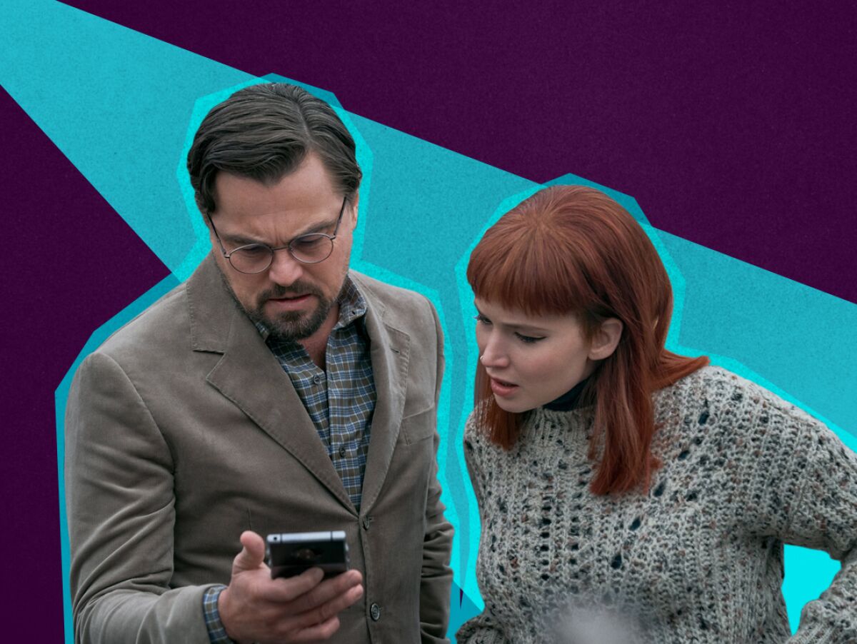 A man and woman look at a phone with concerned expressions.