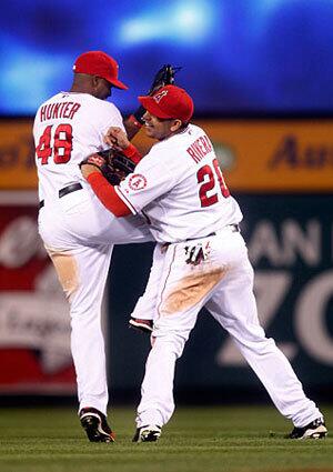 Angels outfielders Torii Hunter and Juan Rivera celebrate a 5-0 victory over Boston on Thursday night in Game 1 of the American League division series at Angel Stadium.