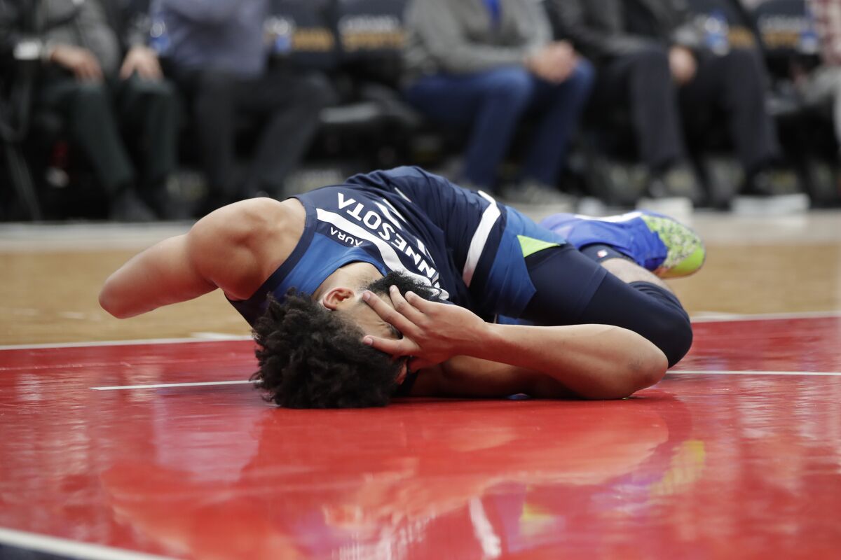Minnesota Timberwolves' Karl-Anthony Towns lies on the court after falling during a dunk in the second half of the team's NBA basketball game against the Washington Wizards, Wednesday, Dec. 1, 2021, in Washington. (AP Photo/Luis M. Alvarez)