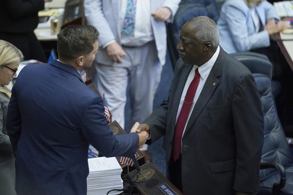 Florida Rep. John Snyder, left, is congratulated by Rep. Webster Barnaby, after the passage of an immigration bill during a legislative session at the Florida State Capitol, Wednesday, March 9, 2022, in Tallahassee, Fla. "I came to America the correct way," said Barnaby, who immigrated from England. "This is all about enforcement. This is all about stopping those people that are illegally bringing people ... directly to Florida from being able to do that." (AP Photo/Wilfredo Lee)