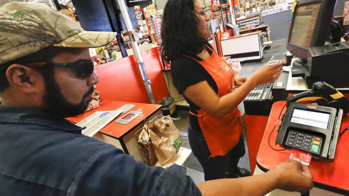 El cajero Janie Thompson espera por Robert Montanez de San Fernando mientras usa si tarjeta con el nuevo dispositivo iEMV en el Home Depot de Burbank.