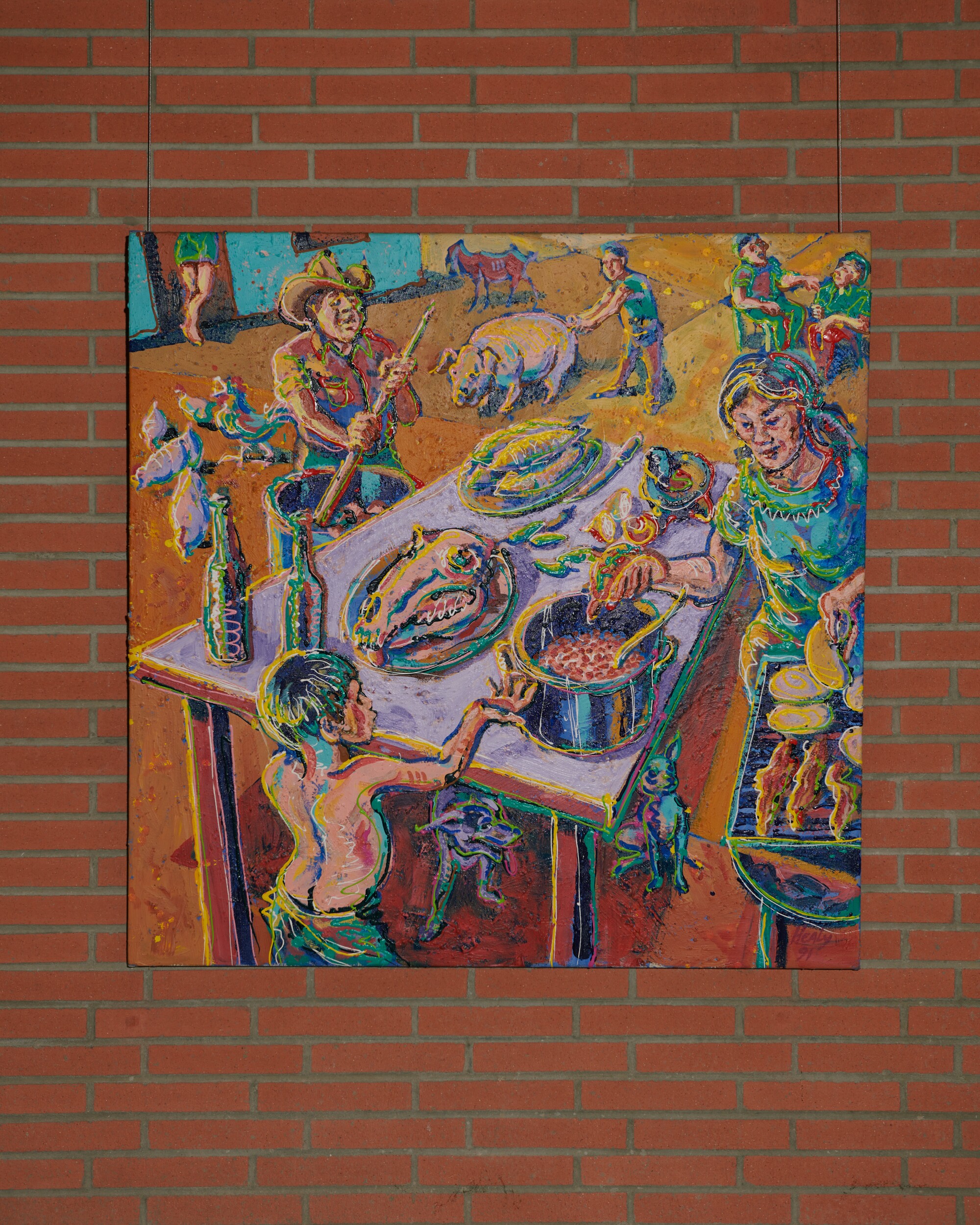 A colorful painting of a family preparing a meal outdoors hangs on a brick wall.