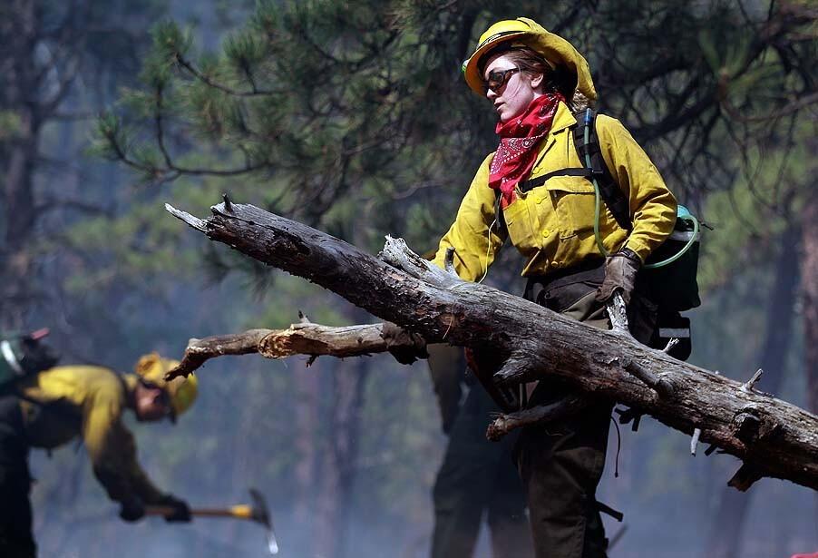 Samantha Marison, an AmeriCorps volunteer firefighter assigned to the El Paso County Sheriff's Office, removes wood fuel to help contain a spot fire in an evacuated area north of Colorado Springs.