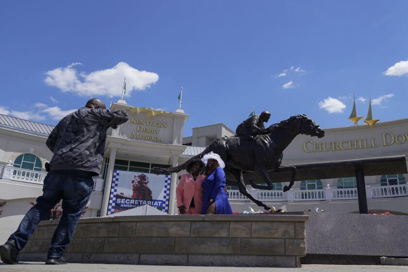 Race fans take photos in front of a statue of Barbaro at Churchill Downs