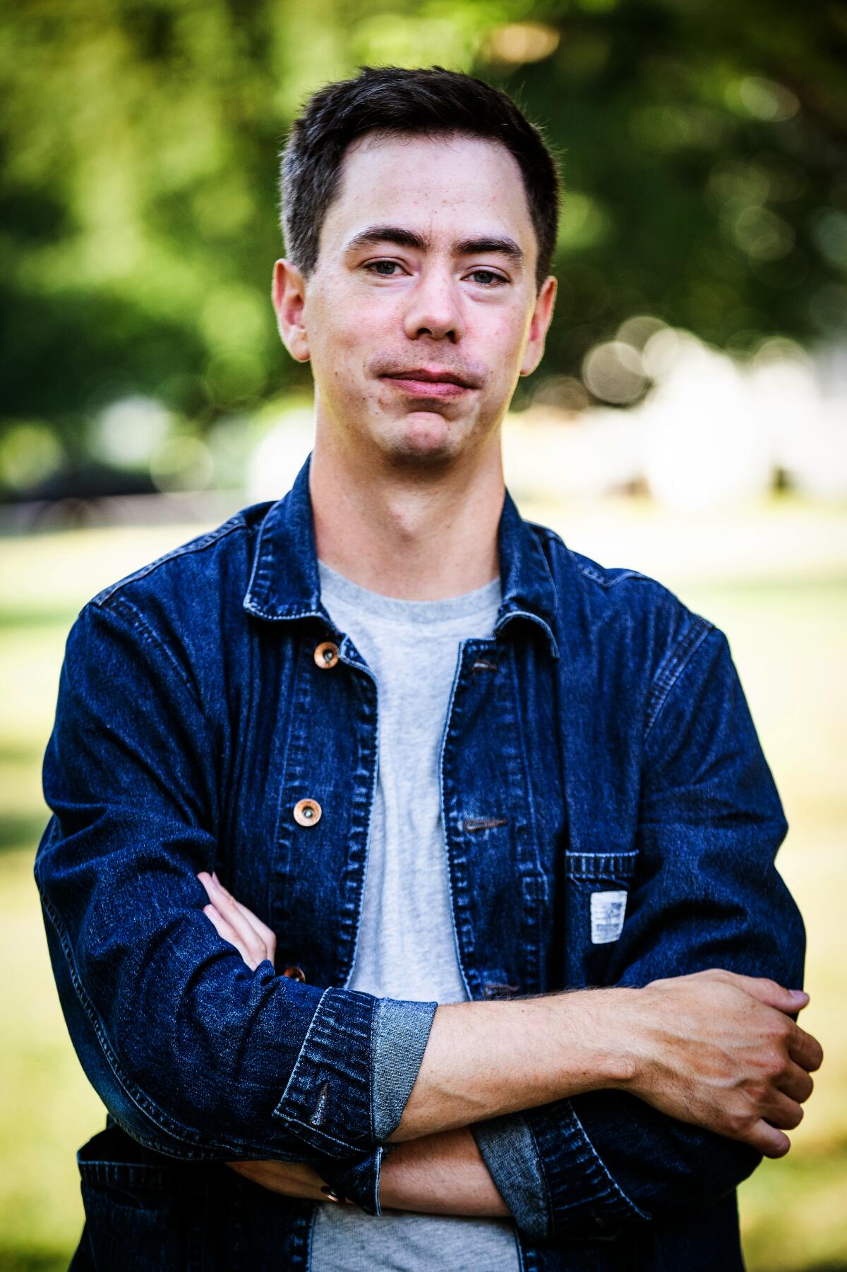 Author Kyle Chayka, in a grey T-shirt and denim jacket, stands with his arms crossed.