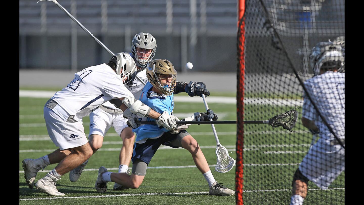 Corona de Mar High attacker Aidan Kelly has the ball knocked free as he takes a shot in front of the net in a boys' lacrosse game against Trabuco Hills on Saturday.