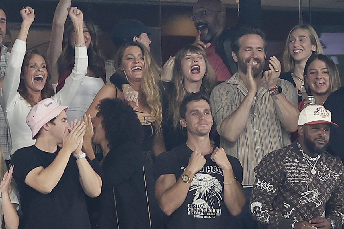 Taylor Swift, Blake Lively and Ryan Reynolds yell or clap while surrounded by other football fans