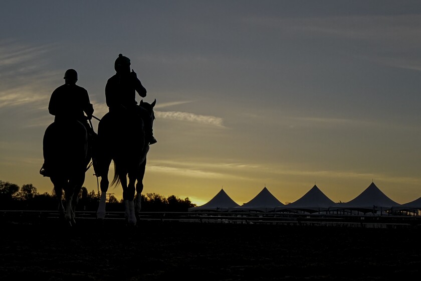Wayne Lukas, left, rides atop Riff next to exercise rider Oscar Quevedo and Secret Oath before a morning workout