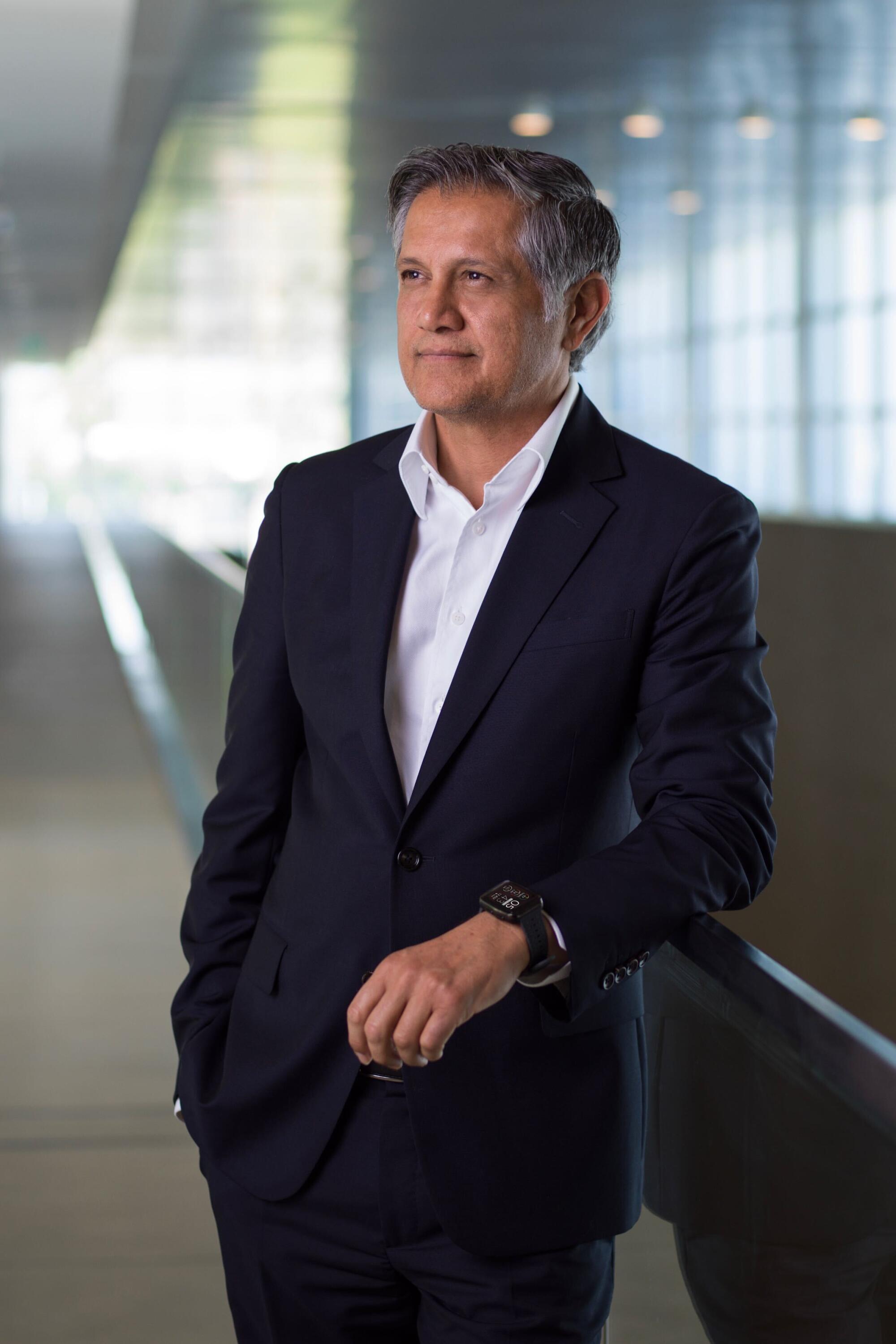 A man wears a white shirt and a dark suit.