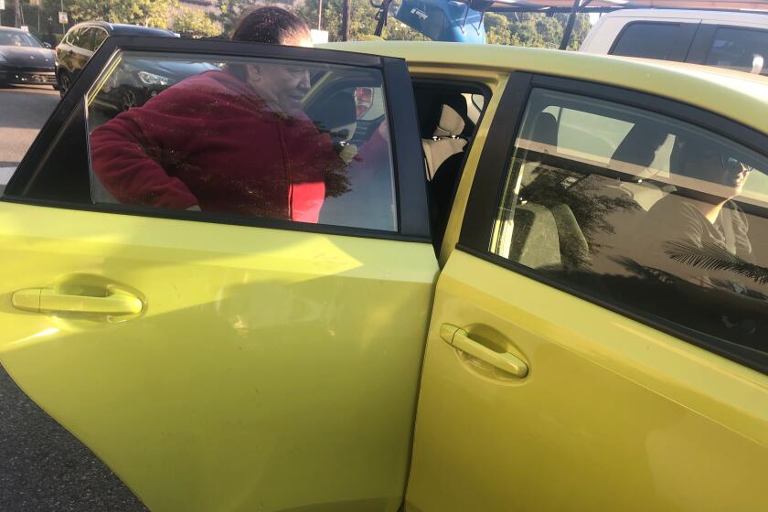 Carmen Solano gets in the back of an Uber after finding out the neighborhood where she works has been evacuated in the Getty fire.