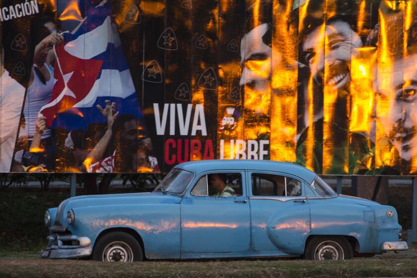 A cabdriver in a classic American car passes a billboard that reads in Spanish, "Long live free Cuba," in Havana on March 14.