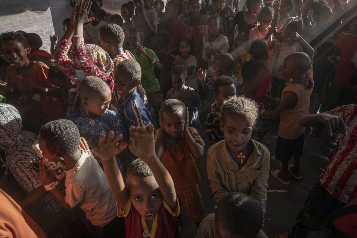Tigray refugee children sing and dance inside a tent run by UNICEF