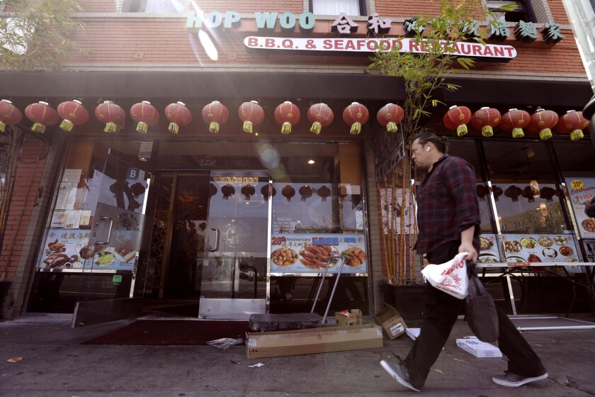 A pedestrian walks past the Hop Woo restaurant on Broadway in Chinatown on May 3.