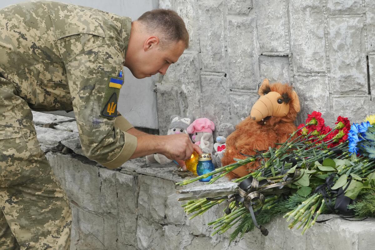 A soldier bends to light a candle that's part of a street memorial in Vinnytsia, Ukraine