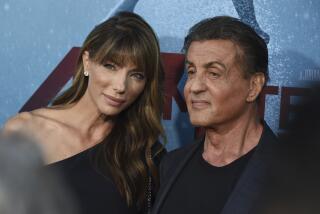 Jennifer Flavin, left, with bangs in a one-shoulder dress leaning and posing with Sylvester Stallone in a dark suit jacket
