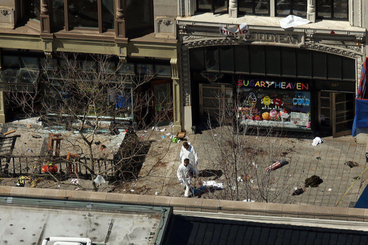 Investigators stand at the scene of bombings at the Boston Marathon on Wednesday. The explosions, which occurred Monday near the finish line of the 116-year-old race, resulted in the deaths of three people, with more than 170 others injured.