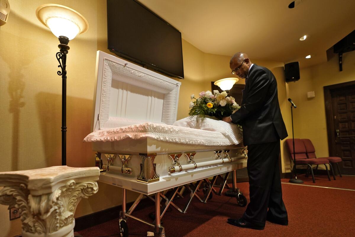 Funeral director placing flowers on a casket