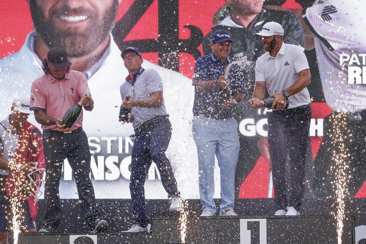 The "4 Aces" team celebrates with champagne after winning the team competition during a ceremony after the final round of the Bedminster Invitational LIV Golf tournament in Bedminster, N.J., Sunday, July 31, 2022. From left to right, Pat Perez, Talor Gooch, Patrick Reed and Dustin Johnson. (AP Photo/Seth Wenig)