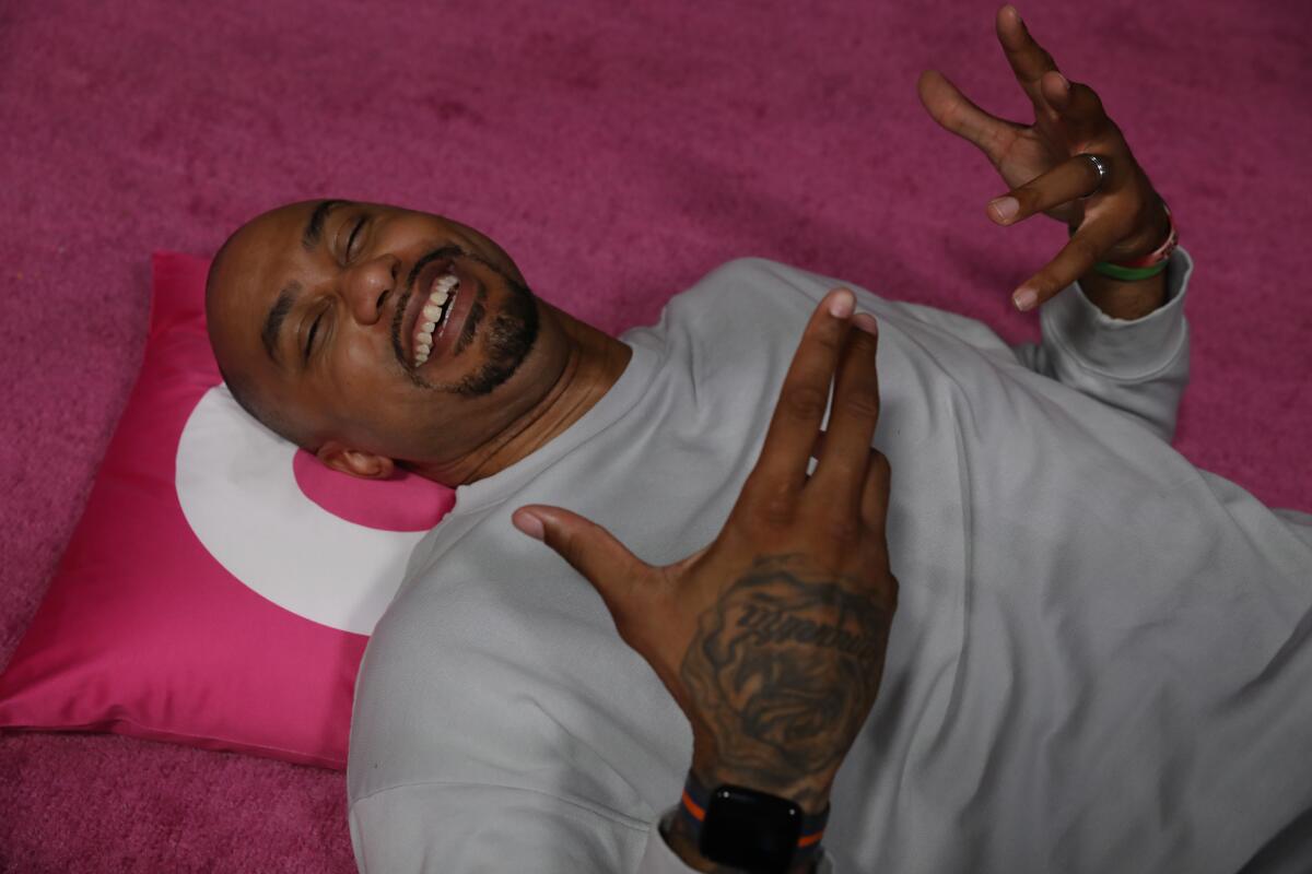 A man lies on a pink carpet with his eyes closed and his head on a pink pillow.
