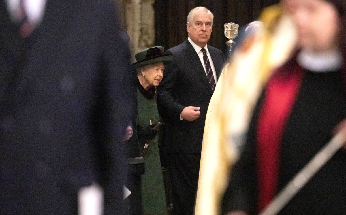 Queen Elizabeth II holds Prince Andrew's arm as they walk into a memorial service.