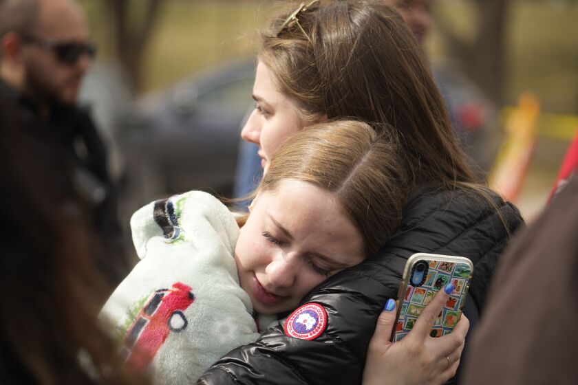 Two women hug after a school shooting at East High School Wednesday, March 22, 2023, in Denver. Two school administrators were shot at the high school Wednesday morning after a handgun was found on a student subjected to daily searches, authorities said. (AP Photo/David Zalubowski)