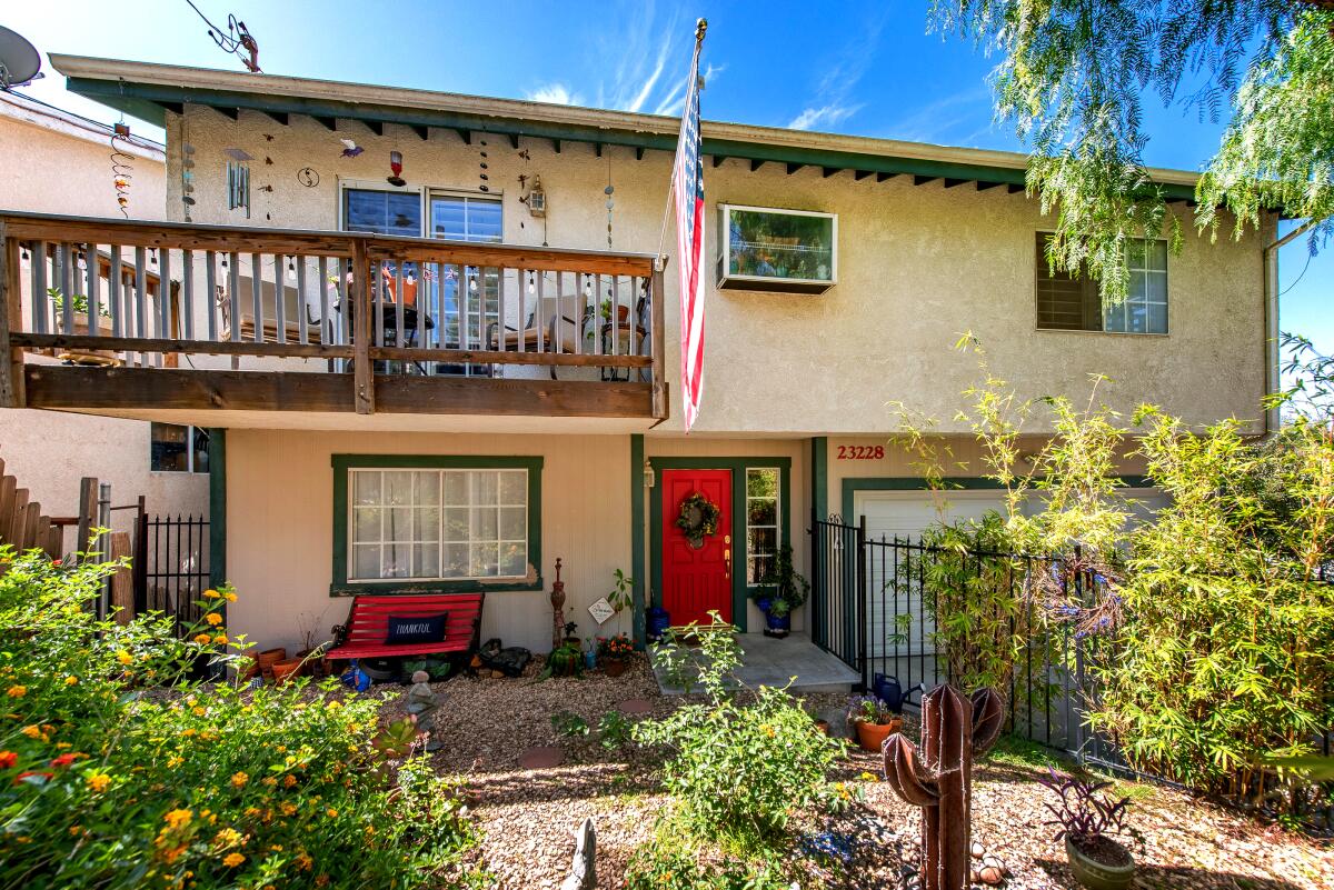 Two story home with balony, flag and plants