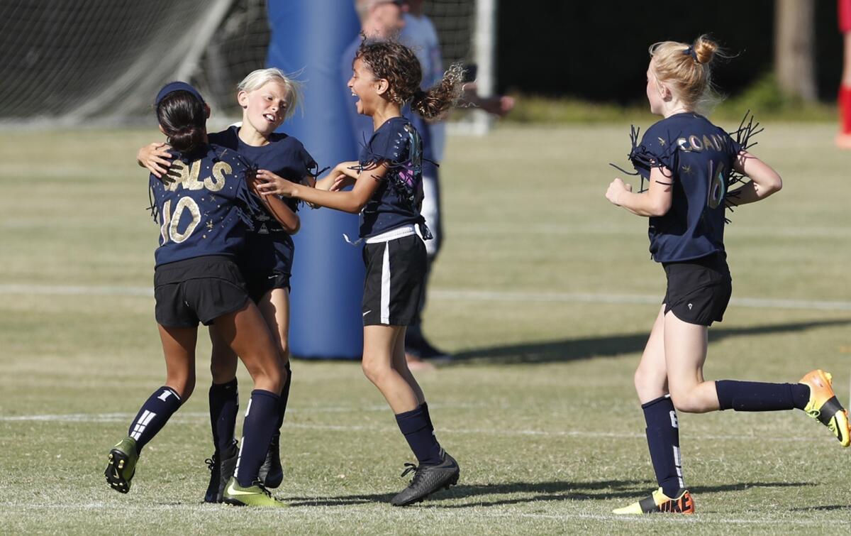 Mariners Elementary's Valery Verdugo, left, and Arianna Presley, right, celebrate with Mia Knox after she scored a goal against Andersen in a girls' third- and fourth-grade Gold Division pool-play match at the Daily Pilot Cup on Wednesday.