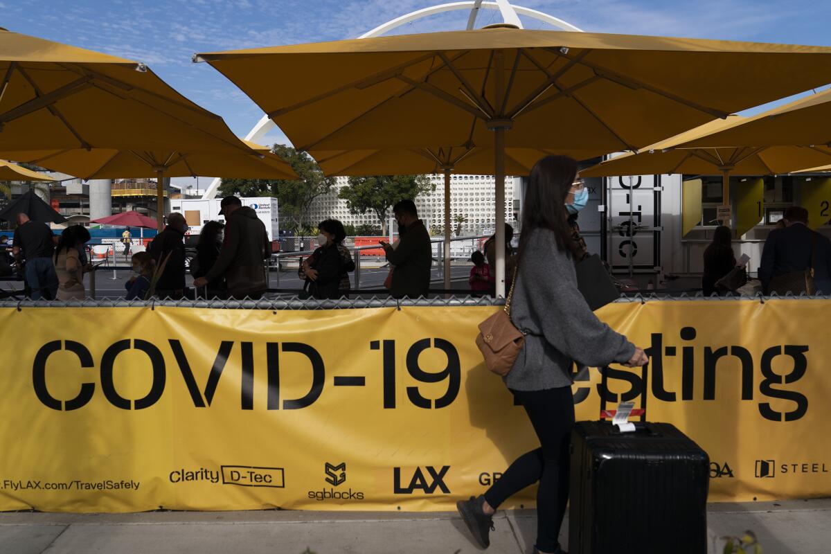 Viajeros hacen fila para que les hagan una prueba diagnóstica de COVID-19 en el Aeropuerto Internacional de Los Ángeles