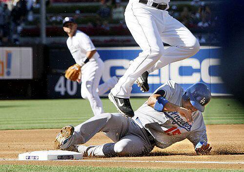 Dodgers shortstop Rafael Furcal slides safely into third base on a double steal, with teammate Orlando Hudson taking second, in the first inning. Furcal and Hudson would score on first baseman James Loney's single.