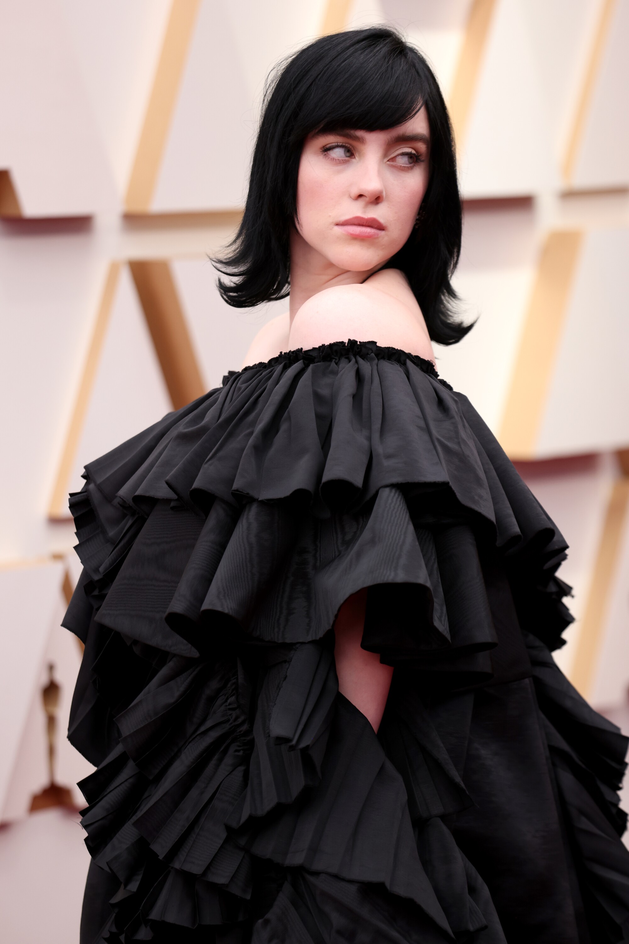A woman in black hair shows off her black gown at the Oscars.