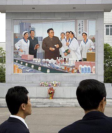 A mural at the entrance of a pharmaceutical factory in Pyongyang, shown in June 2006, depicts North Korean leader Kim Jong Il, who inherited a personality cult his father, Kim Il Sung.