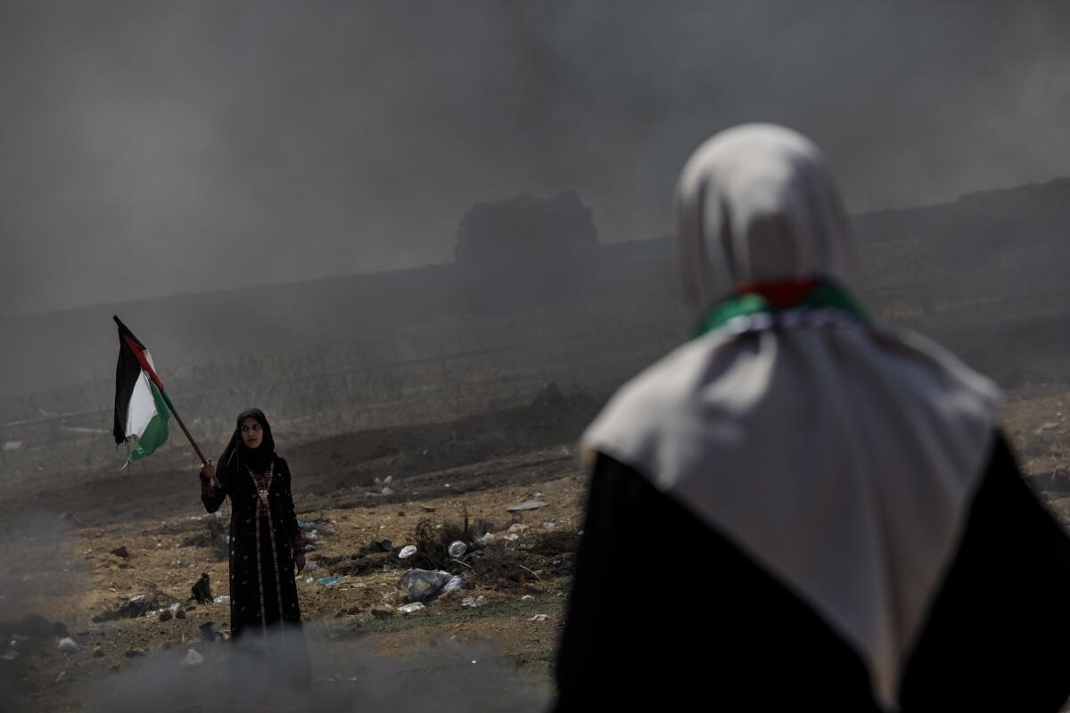 A Palestinian woman waves a flag near the border fence separating Israel and Gaza in a camp east of Gaza City.