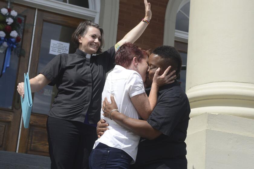 Amber Hamilton and Annice Smith share their first kiss as a married couple in front of by Pastor Brandiilyne Dear on the steps of the Forrest County Courthouse in Hattiesburg, Miss.