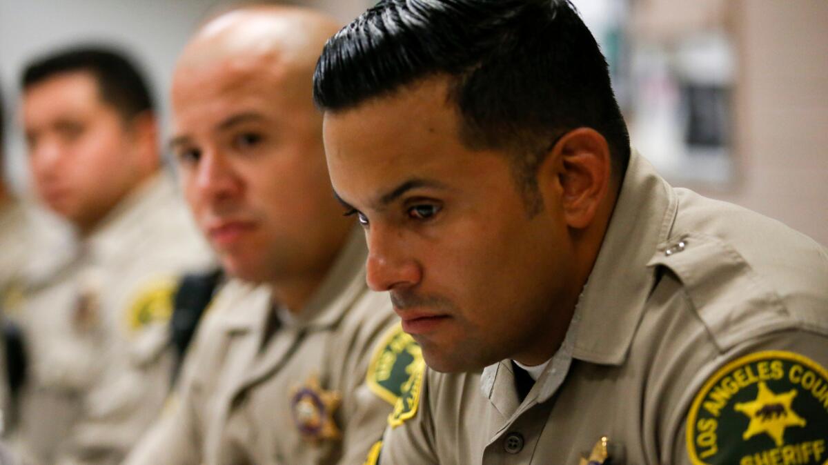 In the aftermath of the ambush slayings of five police officers in Dallas, Los Angeles County Sheriff's Deputies M. Guevara and A. Federico listen during their afternoon briefing at the Compton Sheriff Station.