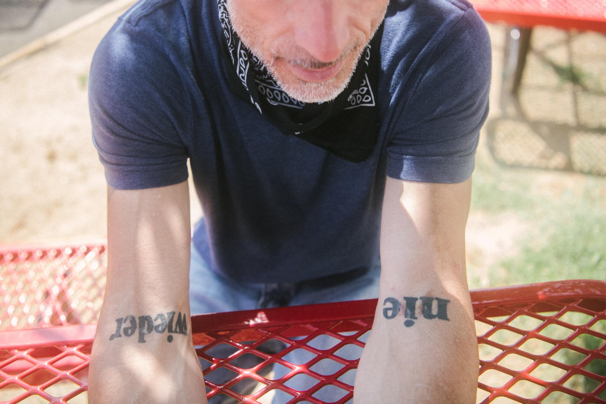 A man shows the tattoos on his arms. 