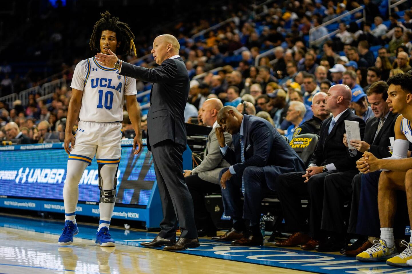 UCLA guard Tyger Campbell (10) talks with coach Mick Cronin on the sideline during the first half of a game against Long Beach State on Nov. 6 at Pauley Pavilion.