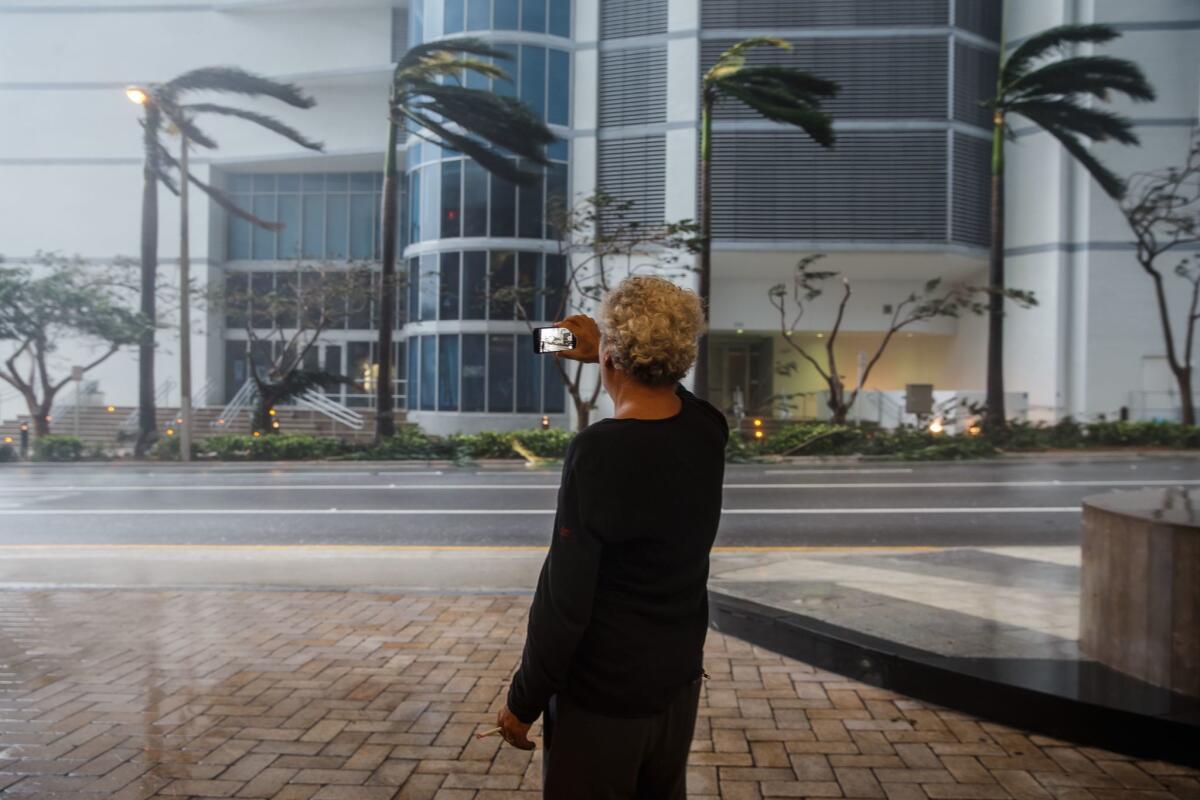 A man attempts to record the furious winds blowing in downtown Miami.