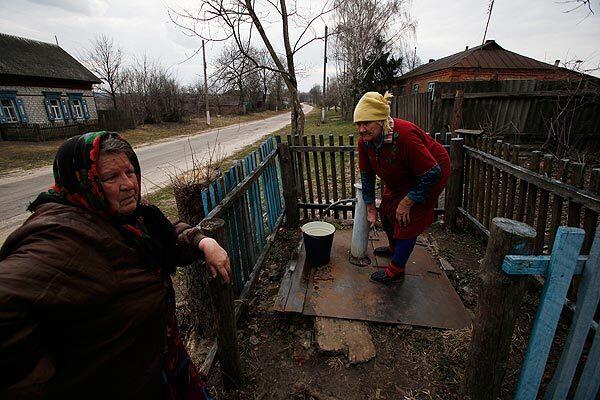 After the Chernobyl catastrophe the authorities replaced all the old water wells in Stary Vyshkov with one artesian well, a water-pressure tower and a system of water fountains. But electric power is very often cut off and that cuts off the water supply too. In summer, even with power on, water pressure is not sufficient. These old women complain of very low water pressure as they are trying to fill a bucket.