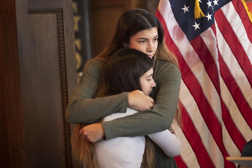 Orange, CA - May 27: Taylor Ybanez, top, consoles her cousin, Alexis Cloonan, 6-year-old shooting victim Aiden Leos's sister, after Alexis spoke along with OC District Attorney Todd Spitzer and OC Supervisor Don Wagner spoke at a press conference on the freeway shooting that took the life of a 6-year-old Aiden Leos at Watson's Soda Fountain and Cafe in Orange Thursday, May 27, 2021. They were joined by business owner Billy Skeffington (owner of Watson's Soda Fountain and several OC businesses), Mario Marovic, owner of Lounge Group, announcing the increase in reward for information leading the the arrest of Aiden's killer. Supervisor Don Wagner's initial matching of the family's $50,000 reward has spurred a community outpouring of donations. The reward total keeps increasing and the community wants to see justice done for Aiden Leos's family. (Allen J. Schaben / Los Angeles Times)