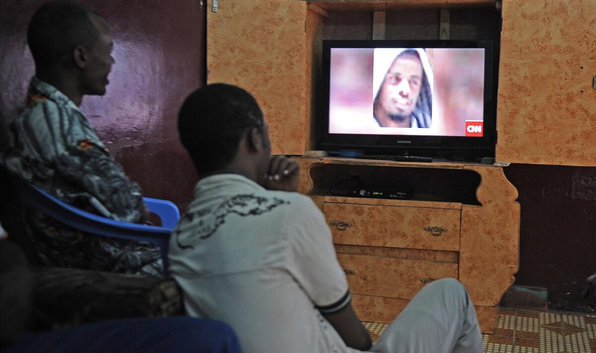 Somali men watch a news broadcast Sept. 6 showing a portrait of slain Shabab leader Ahmed Abdi Godane.