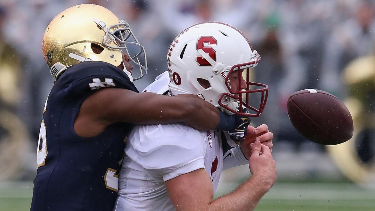 Stanford's Kevin Hogan, right, fumbles the ball after being hit by Notre Dame's Cole Luke during the Fighting Irish's 17-14 win Saturday.
