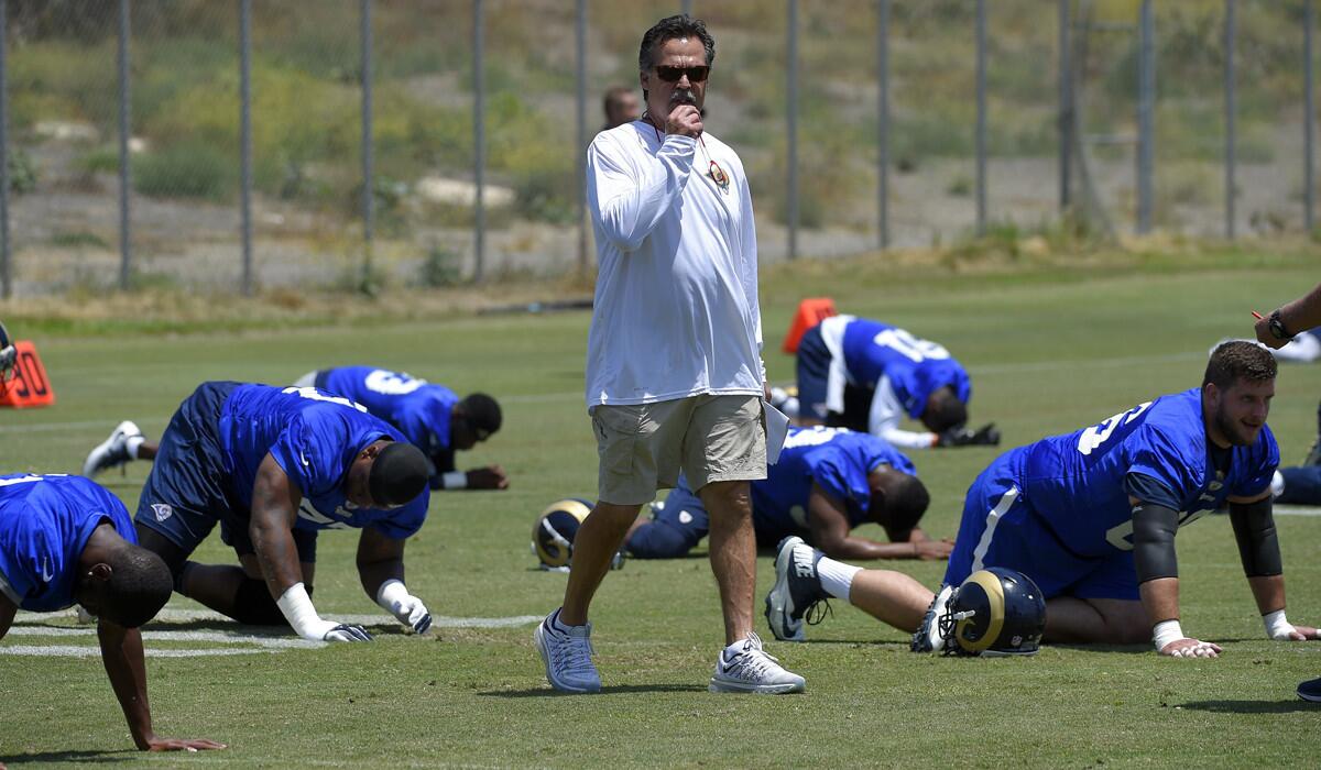 Rams Coach Jeff Fisher walks on the field as players stretch during practice on Friday in Oxnard.