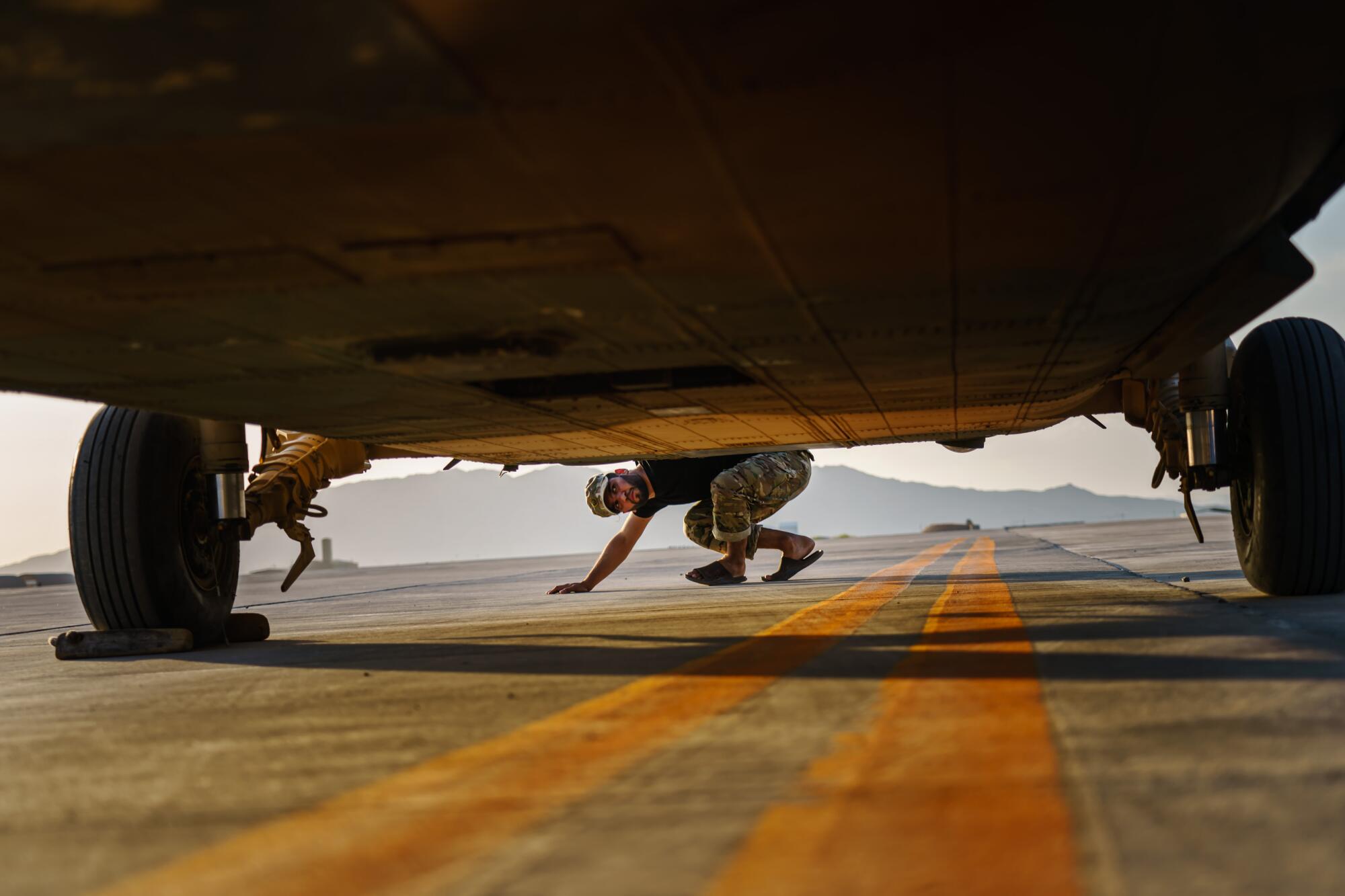 An airman checks for damage caused by gunfire from the Taliban on the UH-60