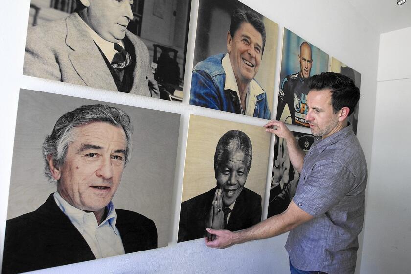 Co-founder Mike Lastrina with an assortment of his favorite personalities printed on wood at the Woodsnap headquarters in Irvine.