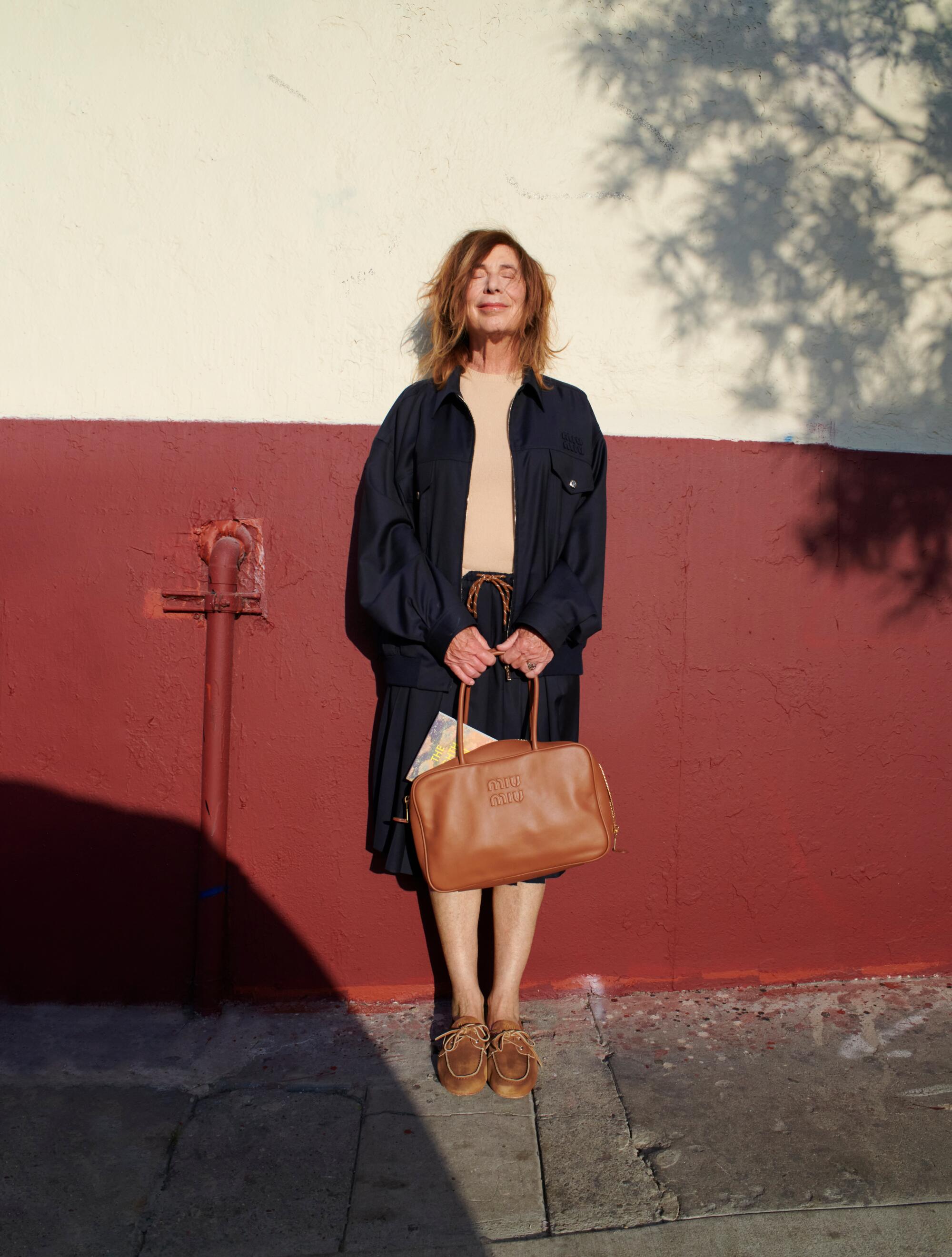 Chris Kraus wears Miu Miu sweater, jacket, skirt, shoes and bag.