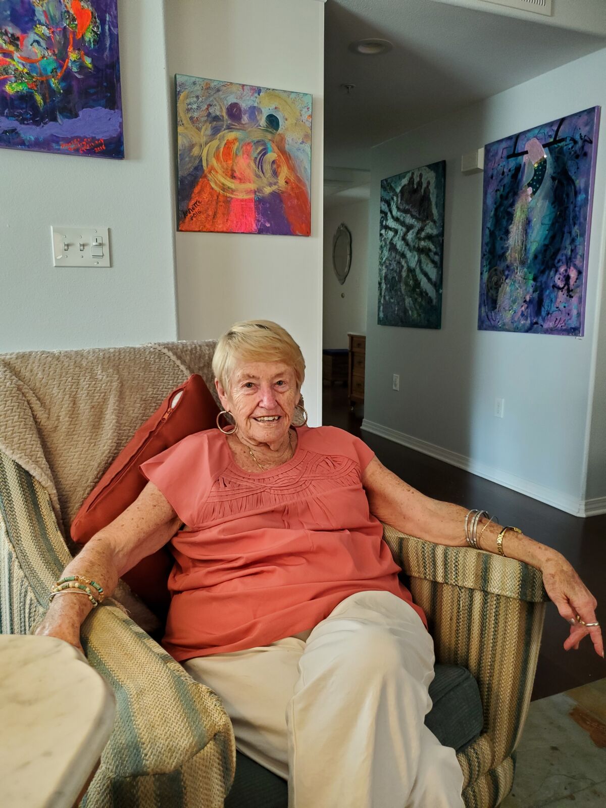 La Jolla resident and ovarian cancer survivor Annette McElhiney is surrounded by paintings she created.