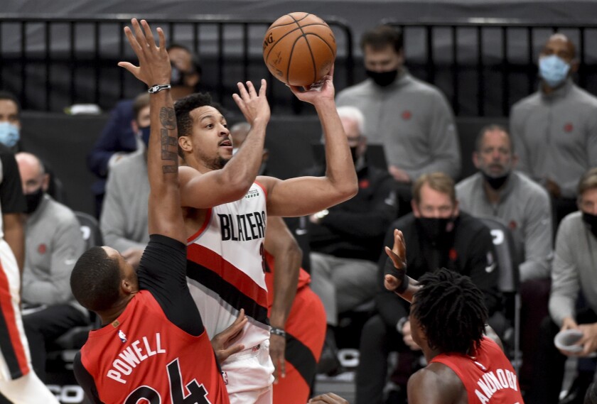 Portland Trail Blazers guard CJ McCollum, center, drives to the basket on Toronto Raptors guard Norman Powell, left, and forward OG Anunoby, right, during the second half of an NBA basketball game in Portland, Ore., Monday, Jan. 11, 2021. The Blazers won 112-111. (AP Photo/Steve Dykes)