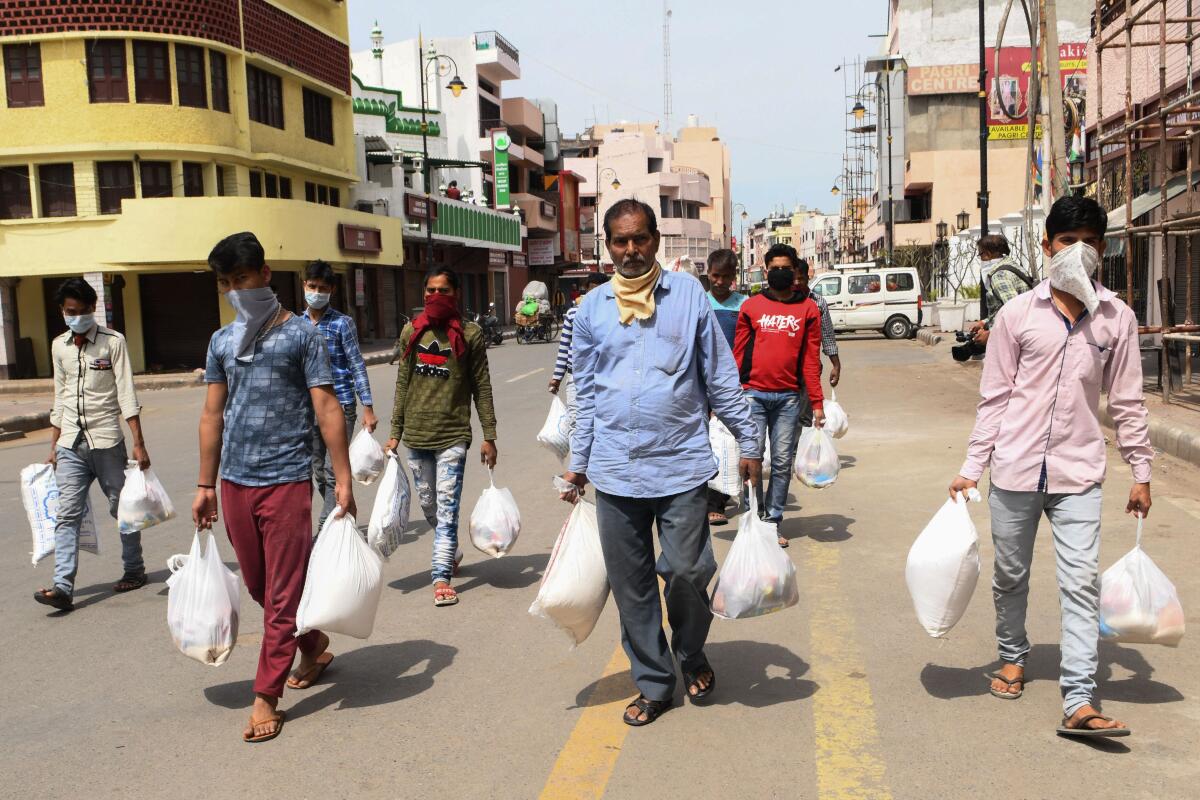 People carry grocery items distributed by volunteers in Amritsar, India.