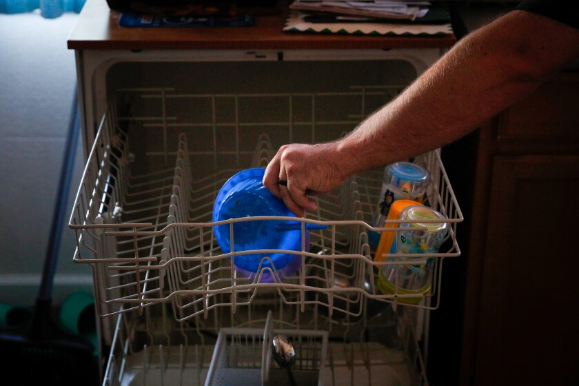 Man loads the dishwasher at his home.