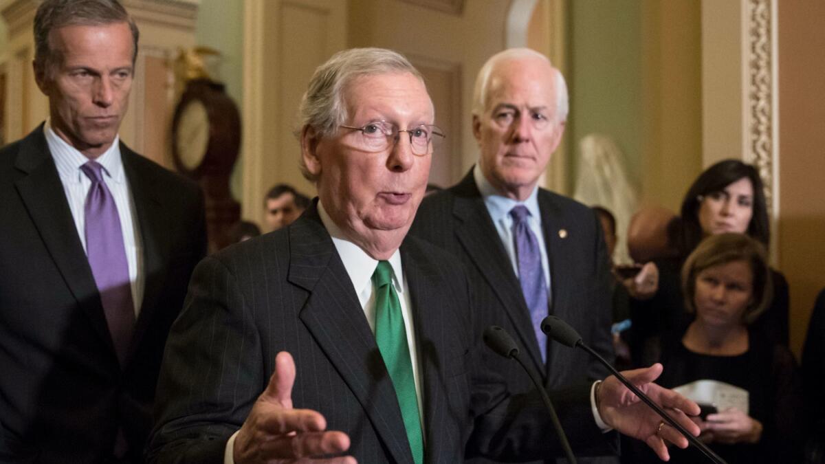 Senate Majority Leader Mitch McConnell (R-Ky.), flanked by Sen. John Thune (R-S.D.), left, and Majority Whip John Cornyn (R-Texas), speaks to reporters on Oct. 17 at the Capitol.